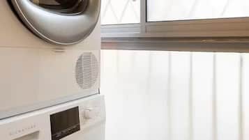 A stacked washer and dryer unit in a laundry room with a window.
