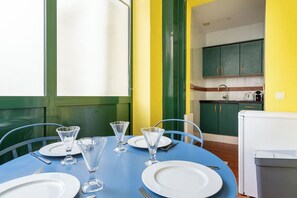 A dining table set with plates, glasses, and cutlery, with a kitchen in the background. - Le 10 Jean Daumas Studio avec Loggia (Cannes)