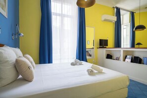 A hotel room with a bed, a desk, a chair, a lamp, a shelf with books and a phone, and a window with curtains. - Le 10 Jean Daumas Studio avec Loggia (Cannes)