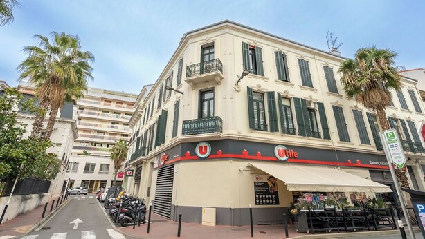 Un hotel Uitaly amb façana blanca, persianes verdes i un balcó.