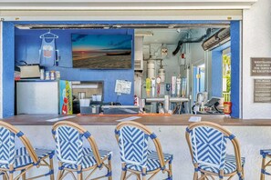 A bar area with a counter, bar stools, and a view of the beach.