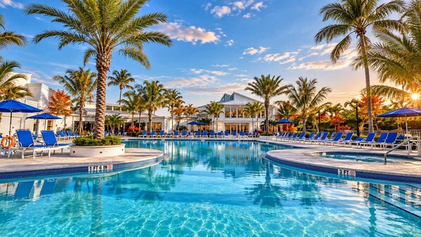 A pool with clear blue water, surrounded by lounge chairs and palm trees.
