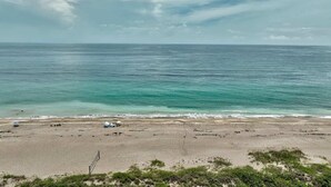 A beach with clear turquoise water, a sandy shore, and some vegetation in the foreground.