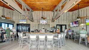 A bar area with a wooden ceiling, multiple TVs, and bar stools.
