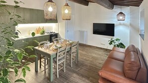 Ett modernt kök med träbjälkar, en matplats med bord och stolar samt en brun lädersoffa.