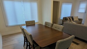 Un coin repas avec une table en bois et six chaises, un canapé et un luminaire au plafond.