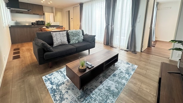 Un salon moderne avec un canapé, une table basse et une vue sur la cuisine et la salle à manger.