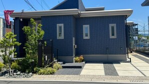 Un bâtiment moderne à deux étages, doté d’une façade bleu foncé, d’un toit plat et d’un petit porche à l’avant.