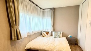 Un dormitorio con cama, cortinas, una mesita de noche y un armario.