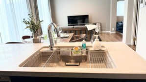 A modern kitchen with a double sink, stainless steel faucet, and a built-in oven. - Akikawa Koshi 7 | 15 min to TSMC | Entire 4LDK House | Up to 7 Guests (合志市)