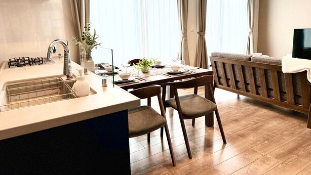 A modern kitchen with a gas stove, sink, and dining area with a table and chairs. - Akikawa Koshi 7 | 15 min to TSMC | Entire 4LDK House | Up to 7 Guests (合志市)