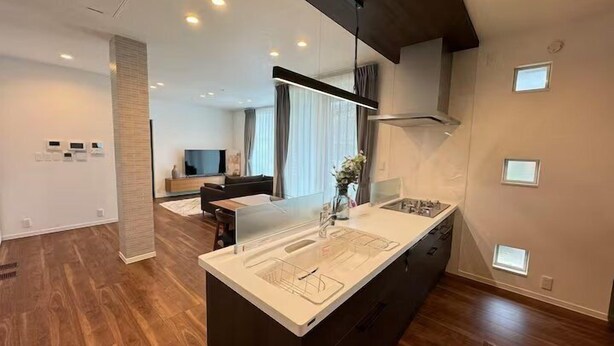 A modern kitchen with a central island, built-in appliances, and a dining area with a sofa and TV. - Akikawa Koshi 5 | 15 min to TSMC | Entire 3LDK House | Up to 4 Guests (合志市)