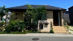 A modern house with a solar panel roof, a small front porch, and a visible manhole cover. - Akikawa Koshi 5 | 15 min to TSMC | Entire 3LDK House | Up to 4 Guests (合志市)