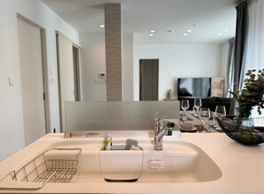 A modern bathroom with a large mirror, a sink with a soap dispenser, and a towel rack. - Akikawa Koshi 5 | 15 min to TSMC | Entire 3LDK House | Up to 4 Guests (合志市)
