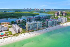 A coastal hotel with multiple buildings, a beach, and a river. - Beachfront Living in a Stunning Condo (Bonita Springs)