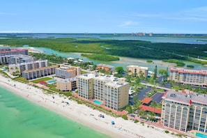 A coastal hotel with multiple buildings, a beach, and a marina. - Beachfront Living in a Stunning Condo (Bonita Springs)