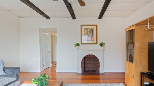 A living room with hardwood floors, a fireplace, a ceiling fan, and a television on a wooden cabinet. - All American Style / 18 min to Manhattan (Carlstadt)