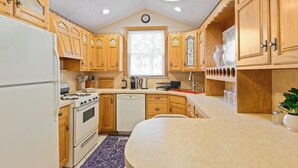 A kitchen with wooden cabinets, a stove, a dishwasher, and a window with blinds. - All American Style / 18 min to Manhattan (Carlstadt)