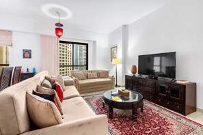 Ein Wohnzimmer mit einer Couch, einem Couchtisch, einem Fernseher und einem großen Fenster.