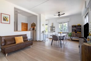 A modern living room with a brown leather sofa, a dining area with a wooden table and chairs, and a kitchen with a stove and cabinets. - Limone Apt · Lake View - Finestra sul Lago (Malcesine)