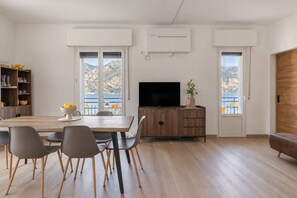 A modern living room with a dining area, a flat-screen TV, and a wooden cabinet. - Limone Apt · Lake View - Finestra sul Lago (Malcesine)