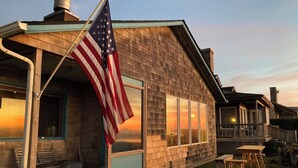 Ein Holzhaus mit Veranda, großen Fenstern und einer amerikanischen Flagge.