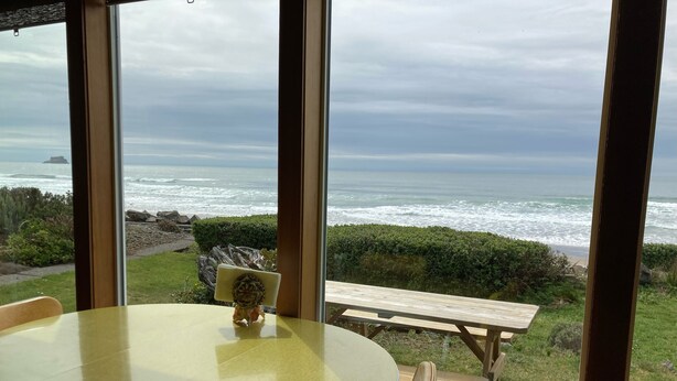Ein Tisch und Stühle in einem Raum mit einem großen Fenster mit Blick auf das Meer.