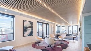 Un ambiente ufficio moderno con soffitto alto, ampie finestre e arredi contemporanei.