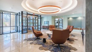 Una hall con una luce a soffitto circolare, porte in vetro e sedute moderne.