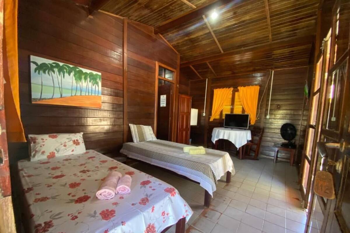 A wooden room with two beds, a TV, and a table.