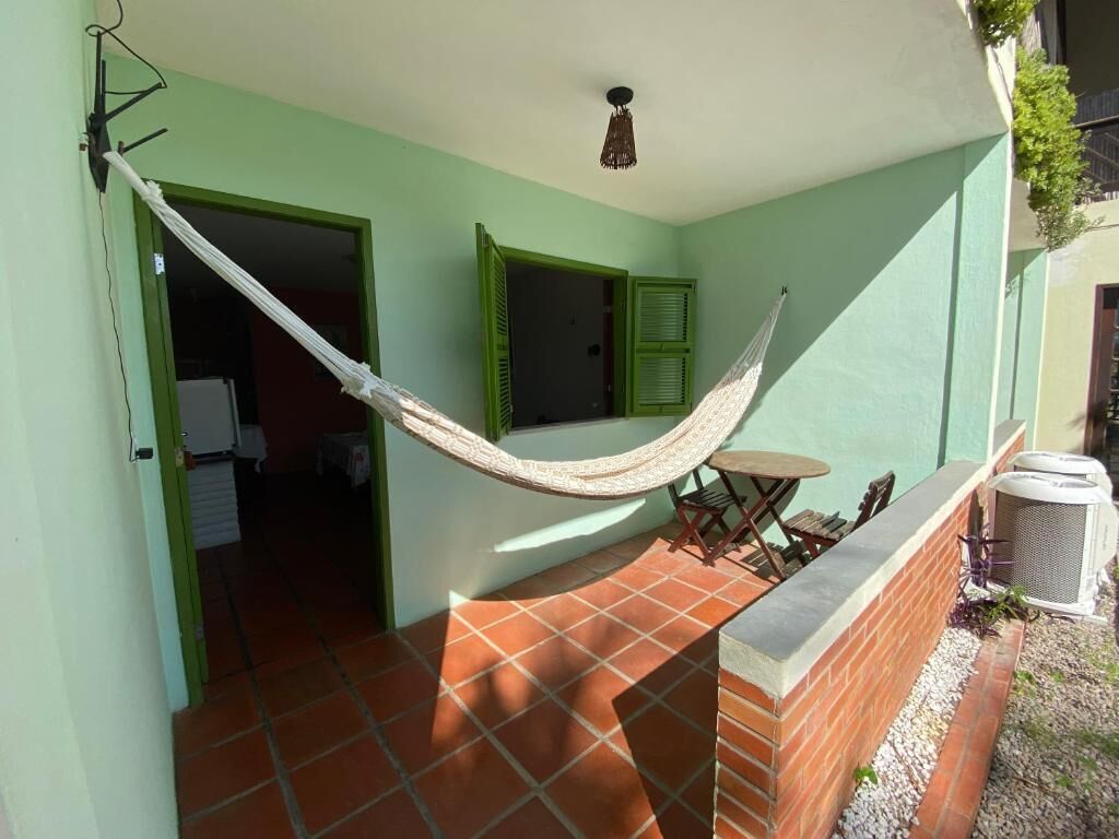 Un hamac sur un balcon, avec un sol carrelé, une petite table et une chaise.