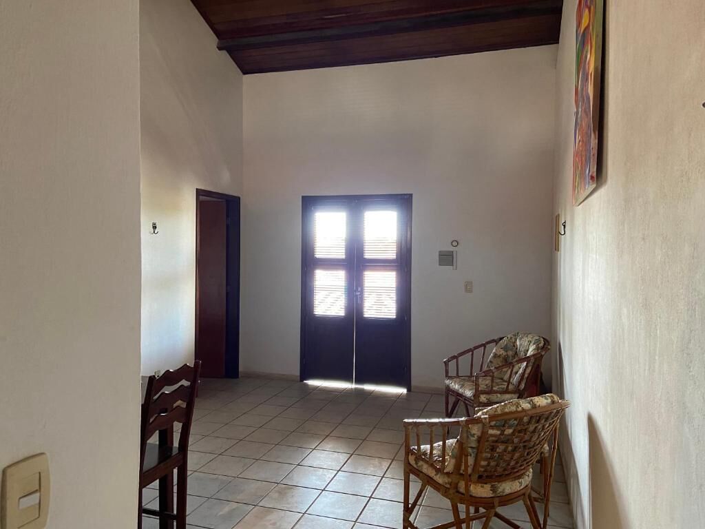 Una habitación con piso de baldosas, una puerta con dos ventanas y dos sillas de mimbre.