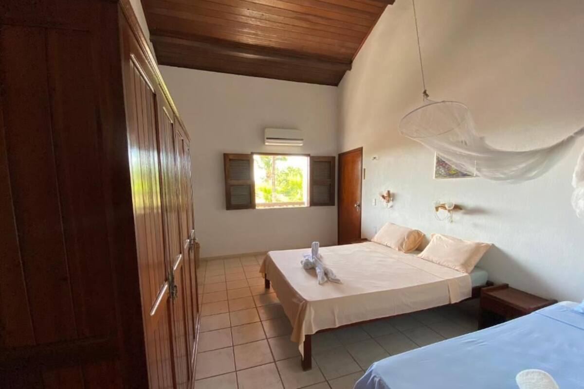 A room with a bed, a wooden wardrobe, a window with shutters, and a hanging light fixture.