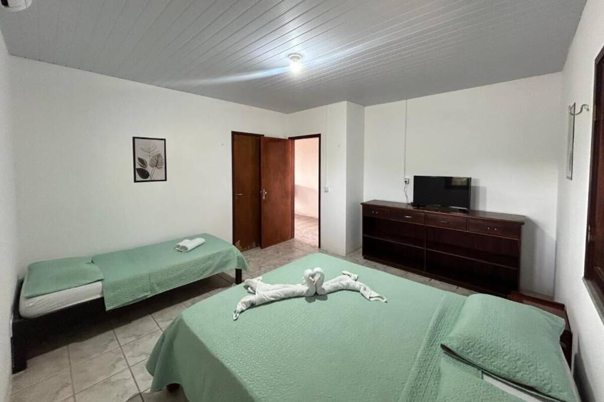 A room with two beds, a television, a desk, and a door leading to another room.