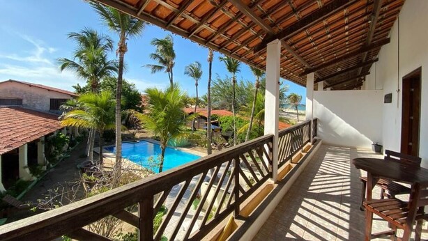 Un balcon fermé offrant une vue sur une piscine et des palmiers.