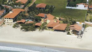 Vue aérienne d’une zone résidentielle côtière, avec des maisons, une plage et un petit plan d’eau.