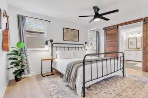 A bedroom with a bed, a ceiling fan, a plant, and a view of the bathroom. - Central Franklin Home, Quiet Street, Outdoor Fun (Franklin)