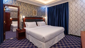 A hotel room with a large bed, a nightstand, a mirror, and a patterned carpet. - Gulf Star Hotel (Dubai)