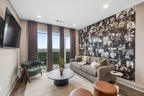 Een moderne woonkamer met een bank, salontafel en een wand vol zwart-witfoto’s.