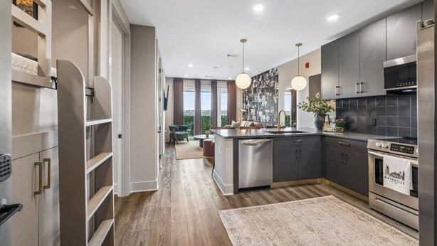A modern kitchen with a central island, stainless steel appliances, and a view of the outdoors.