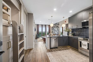 Een moderne keuken met een centraal eiland, roestvrijstalen apparatuur en uitzicht op de omgeving.