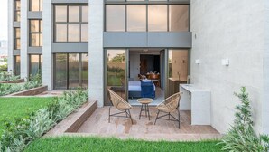 A modern building with a patio area featuring a bed, two chairs, and a small table. - Vivant New Building Seafront in Recife (Recife)