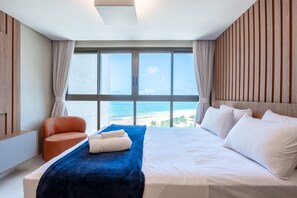 A hotel room with a large bed, a chair, and a view of the beach. - Vivant New Building Seafront in Recife (Recife)