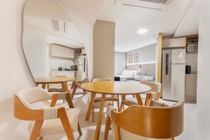 A modern kitchen with a refrigerator, stove, and microwave. There is a dining area with wooden chairs and a round table. - Vivant New Building Seafront in Recife (Recife)