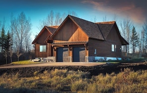 A large, two-story wooden house with a garage, surrounded by trees and a grassy field. - Ski Hill Haven in beautiful Driggs, Idaho.  Sleeps up to 15 guests. (Driggs)