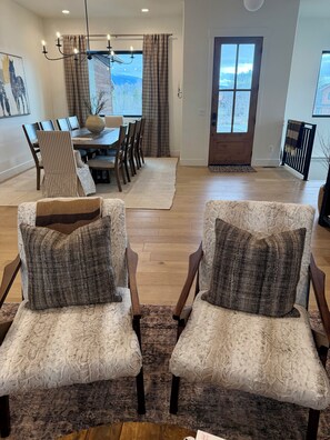 A dining area with a table and chairs, a chandelier, and a view through a window. - Ski Hill Haven in beautiful Driggs, Idaho.  Sleeps up to 15 guests. (Driggs)