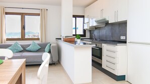 Een moderne keuken met witte kastjes, een centraal eiland en een uitzicht door grote ramen.