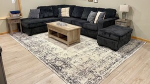 A living room with a sectional sofa, a coffee table, a rug, and framed pictures on the wall. - Charming 3-bedroom house with hot tub in Bailey, perfect for relaxing stays (Bailey)