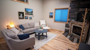 A living room with a sectional sofa, a round coffee table, a fireplace, and framed pictures on the wall. - Charming 3-bedroom house with hot tub in Bailey, perfect for relaxing stays (Bailey)