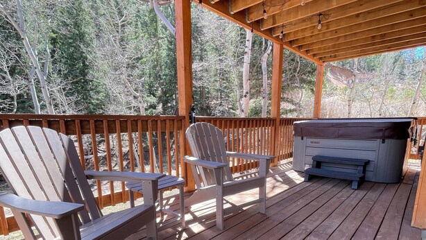 A wooden deck with Adirondack chairs and a hot tub. - Charming 3-bedroom house with hot tub in Bailey, perfect for relaxing stays (Bailey)